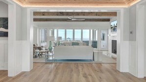 A spacious living area with a large window, a ceiling fan, and a view of the ocean.