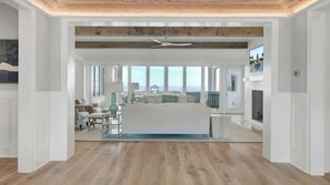 A spacious living area with a large window, a ceiling fan, and a view of the ocean.