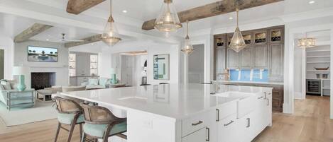 A spacious kitchen with a large island, pendant lighting, and a rustic ceiling beam.