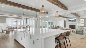 A spacious kitchen with a large island, pendant lighting, and a view to the outside.