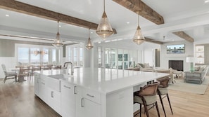 A spacious kitchen with a large island, pendant lighting, and a view to the outside.