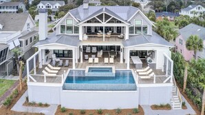 A large, two-story house with a swimming pool, outdoor seating, and a covered patio.