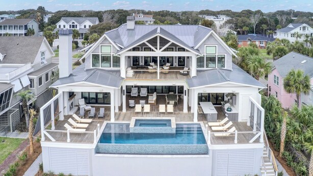 A large two-story house with a swimming pool, outdoor seating, and a covered patio.