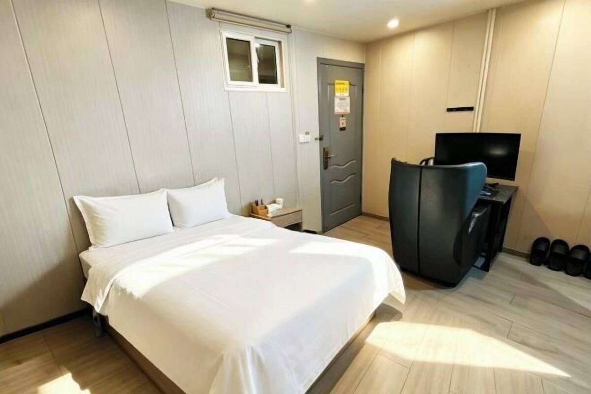 Una habitación de hotel con una cama, televisor, escritorio y puerta.