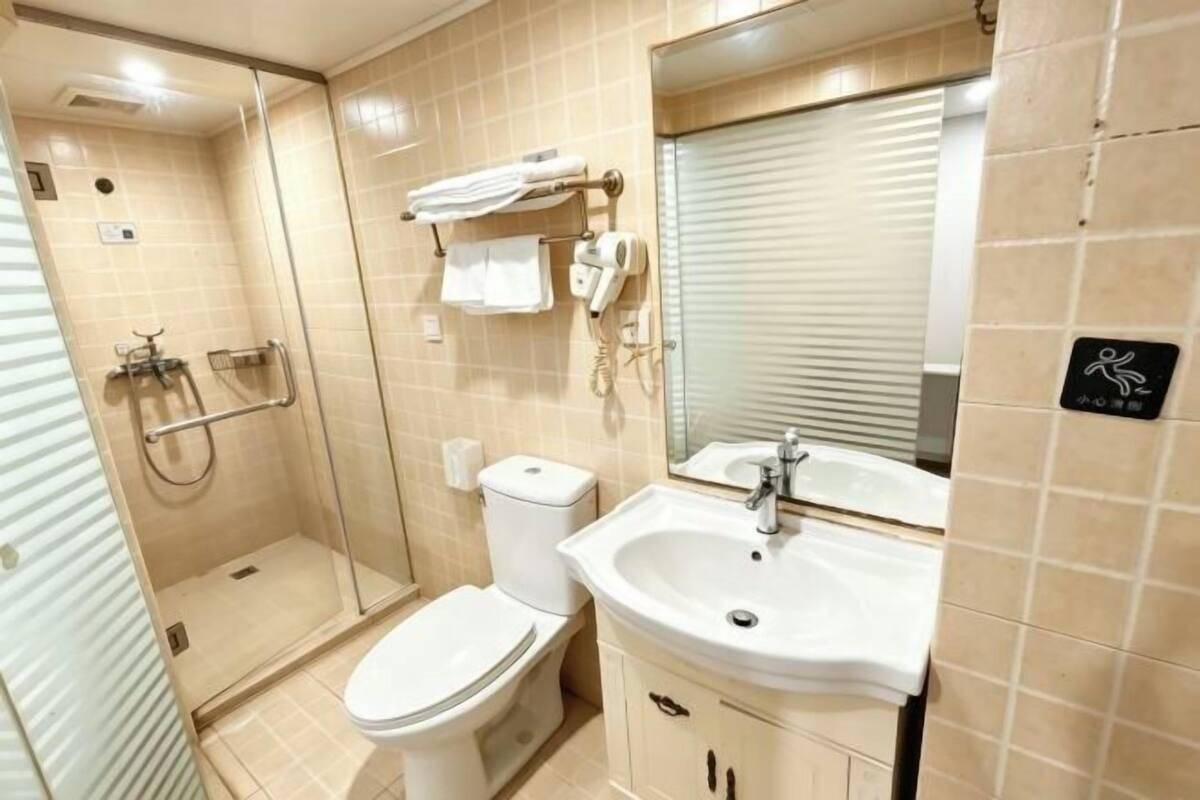 Un baño con inodoro, lavabo, cabina de ducha de vidrio, toallero y espejo.