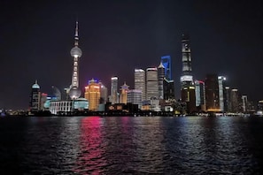 Un horizonte urbano nocturno con edificios iluminados que se reflejan en el agua.