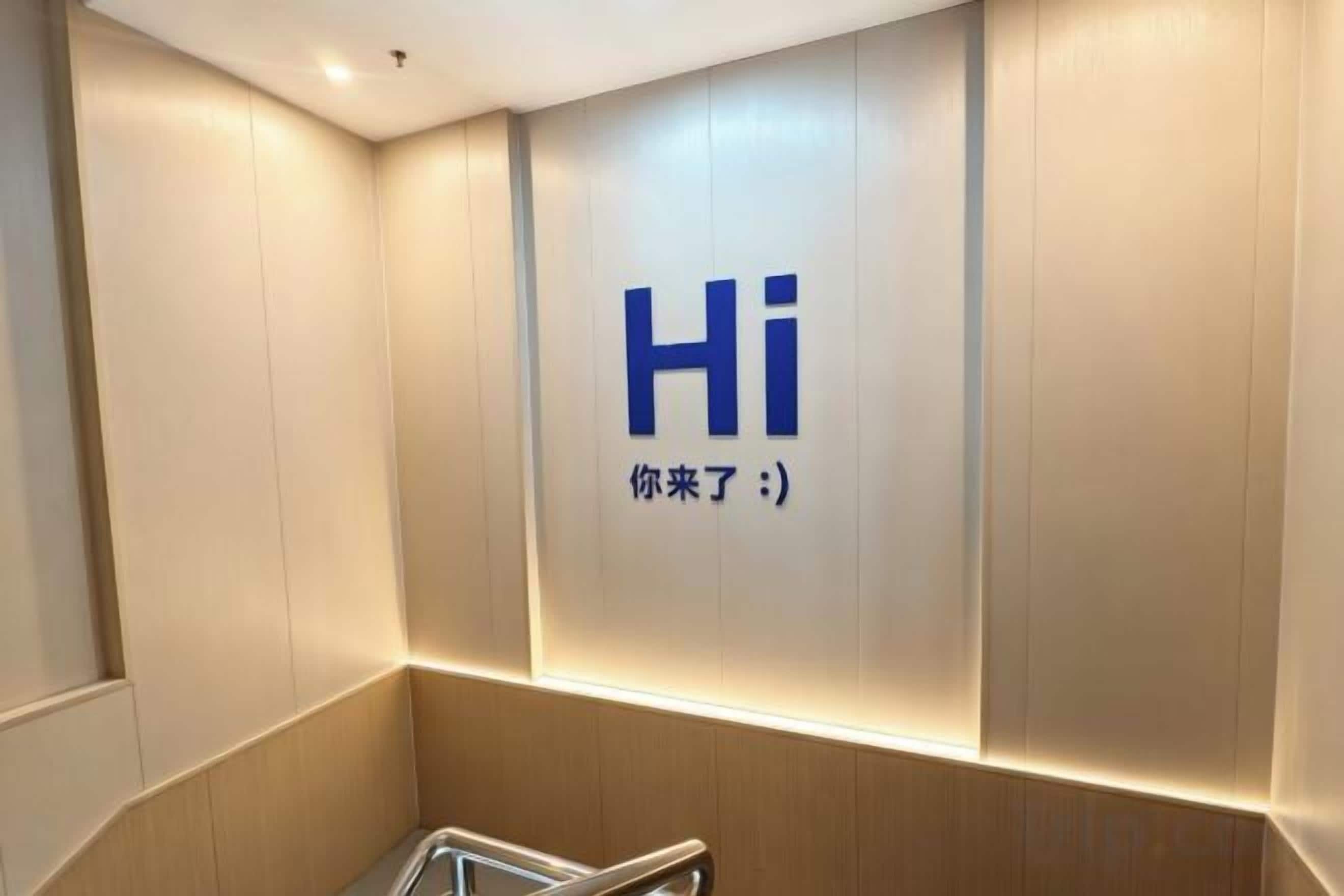 Interior moderno de ascensor con un cartel que dice 'Hola' y un mensaje de bienvenida en un idioma extranjero.