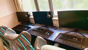 Une pièce comprenant un bureau, trois écrans, un clavier, une souris et un casque audio.