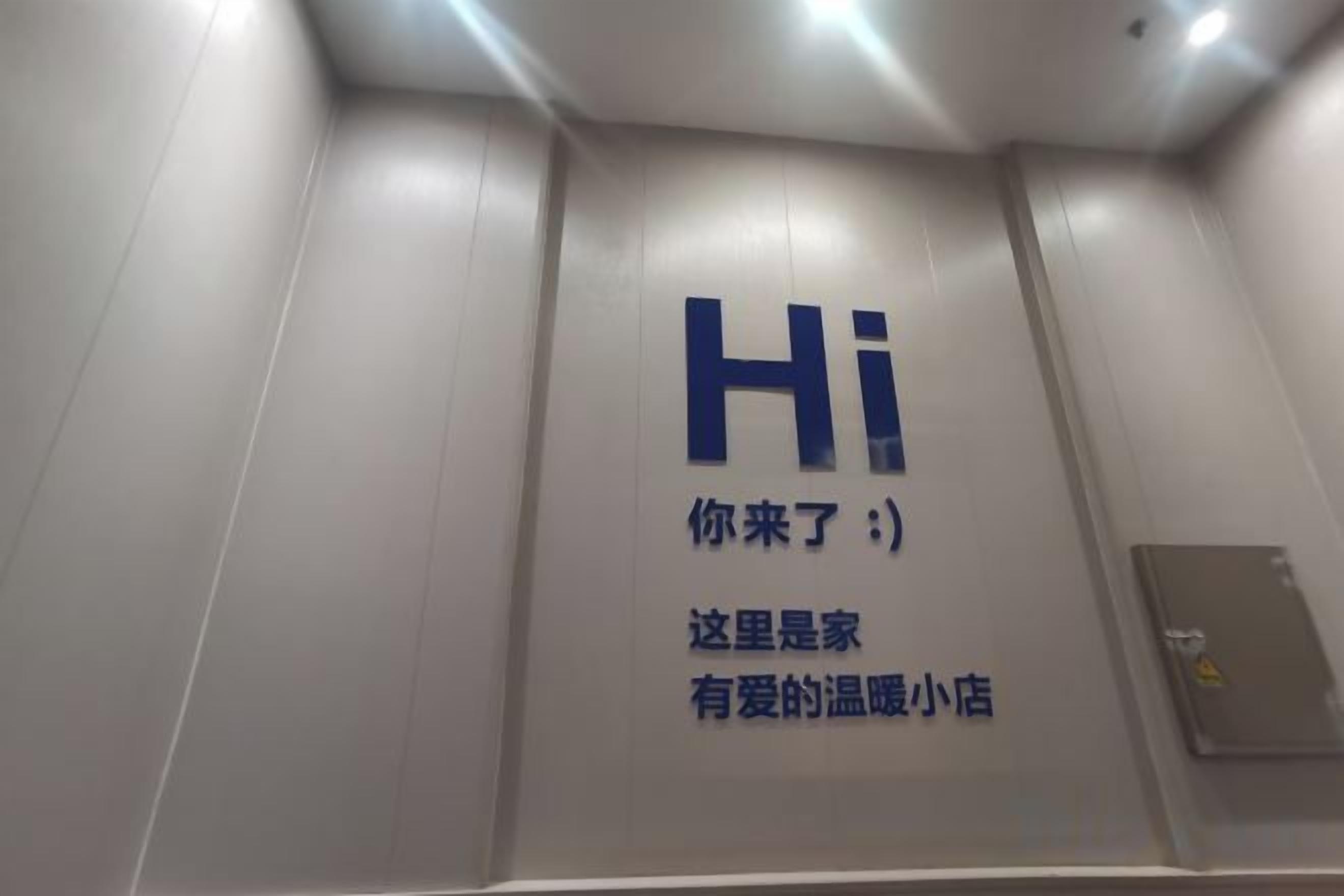 Una pared con un letrero grande que dice 'Hi' y texto en chino, que indica una zona de recepción de hotel.