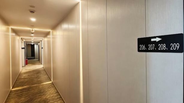 Un couloir d’hôtel avec des panneaux indicateurs indiquant les chambres 206, 207, 208 et 209.