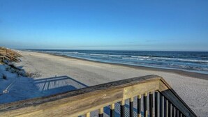 A wooden boardwalk leading to a sandy beach with ocean waves in the background. - Blue Shamu by Topsail Realty (Holly Ridge)