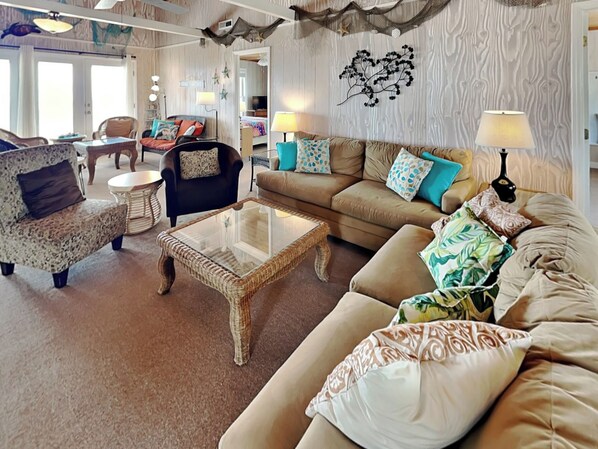 A cozy living room with a sofa, armchairs, a coffee table, and a wall-mounted decoration. - Blue Shamu by Topsail Realty (Holly Ridge)