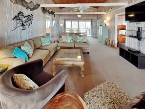 Relax in this stylish living room with a sofa, armchair, and ottoman, surrounded by decorative art and a large window.