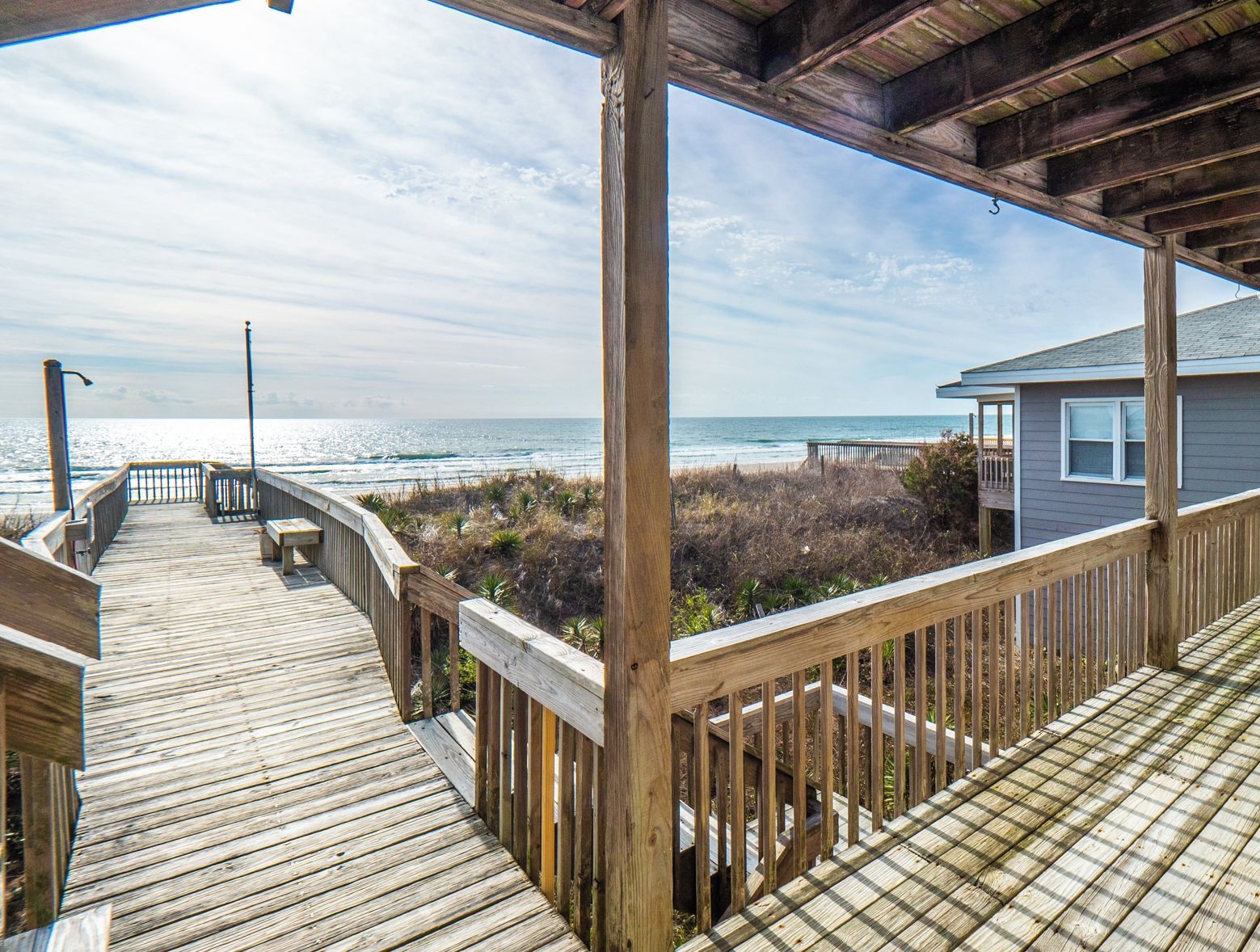 Una terraza de madera con vista al océano y la vegetación de la playa.