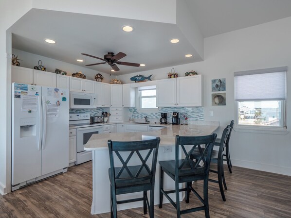 A modern kitchen with white cabinets, a central island, and a ceiling fan. - Sweet Surrender by Topsail Realty (Holly Ridge)