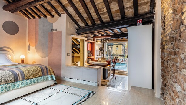 A bedroom with a bed, a bedside table, a chair, and a view of a pool area. - Altiora - Luxury loft in Rome (Roma)
