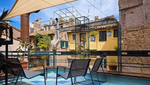 An outdoor pool area with lounge chairs and a view of buildings in the background. - Altiora - Luxury loft in Rome (Roma)