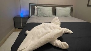 Un lit bien fait, recouvert d’une couverture blanche, dans une chambre d’hôtel.