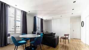 A modern living room with a round table, blue chairs, a black sofa, and a leopard print stool. - Le Gilbert 1 - 10 impasse Gilbert - Vichy (Vichy)