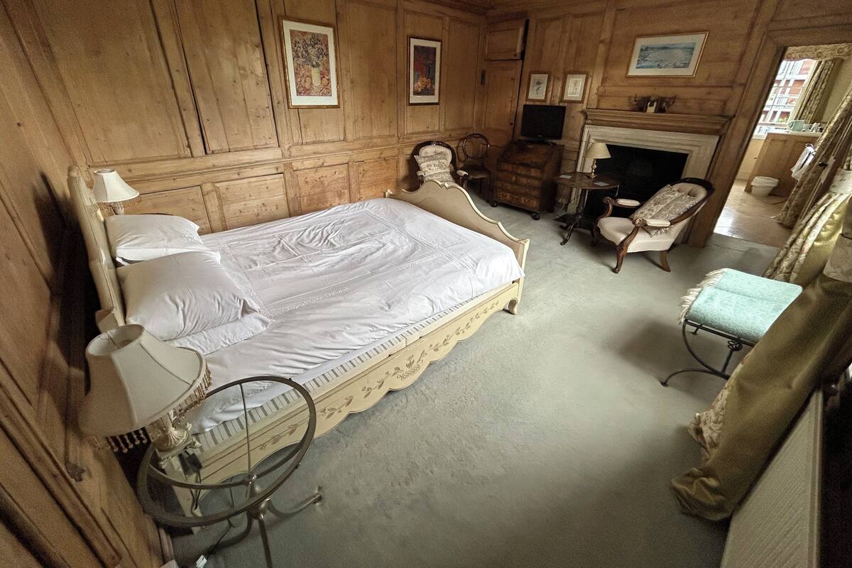 Een klassieke kamer met een groot bed, een televisie, een open haard en houten lambrisering.