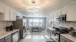 Une cuisine moderne avec des armoires blanches, des appareils en acier inoxydable et un lustre.