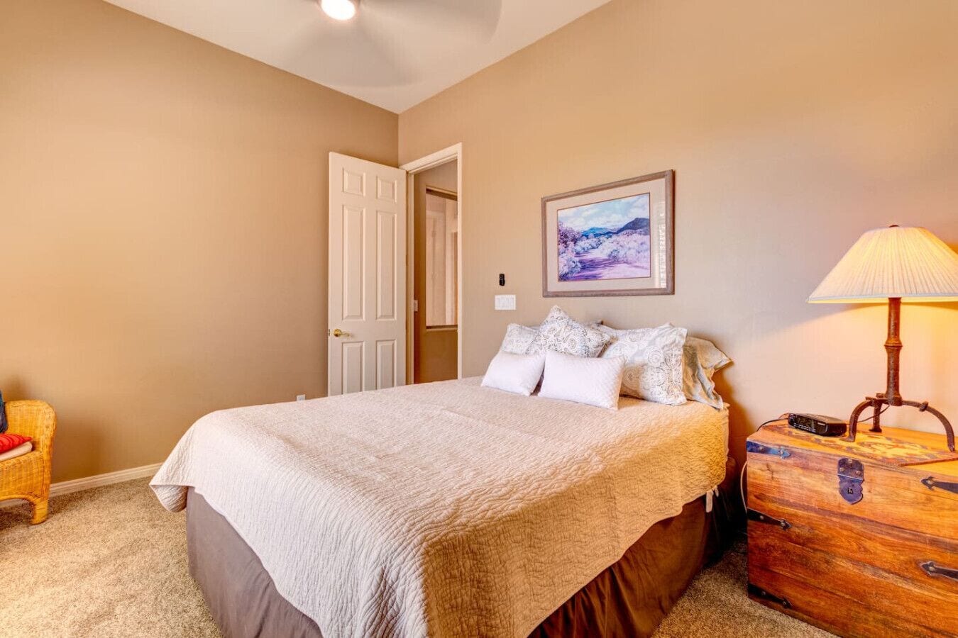 A bedroom with a bed, a dresser, a lamp, and a painting on the wall.