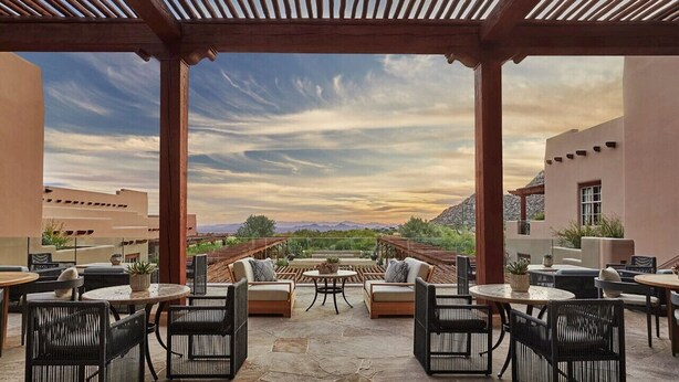 An outdoor patio with seating and tables, a pergola overhead, and a view of mountains in the distance. - Troon North Private Pool & Spa (Scottsdale)