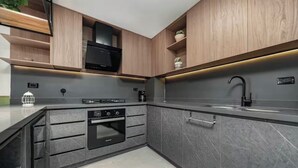 Une cuisine moderne avec des meubles de couleur gris foncé, une cuisinière noire et un évier en acier inoxydable.