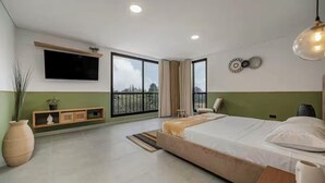 Une chambre à coucher moderne avec un grand lit, un téléviseur fixé au mur et un balcon avec vue.