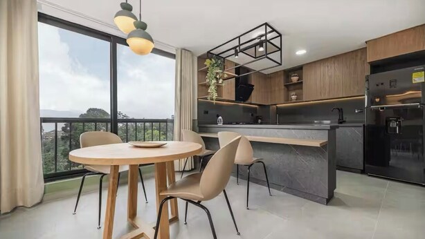 Une cuisine moderne dotée d’un îlot central, de meubles en bois et d’une grande fenêtre offrant une vue sur la ville.