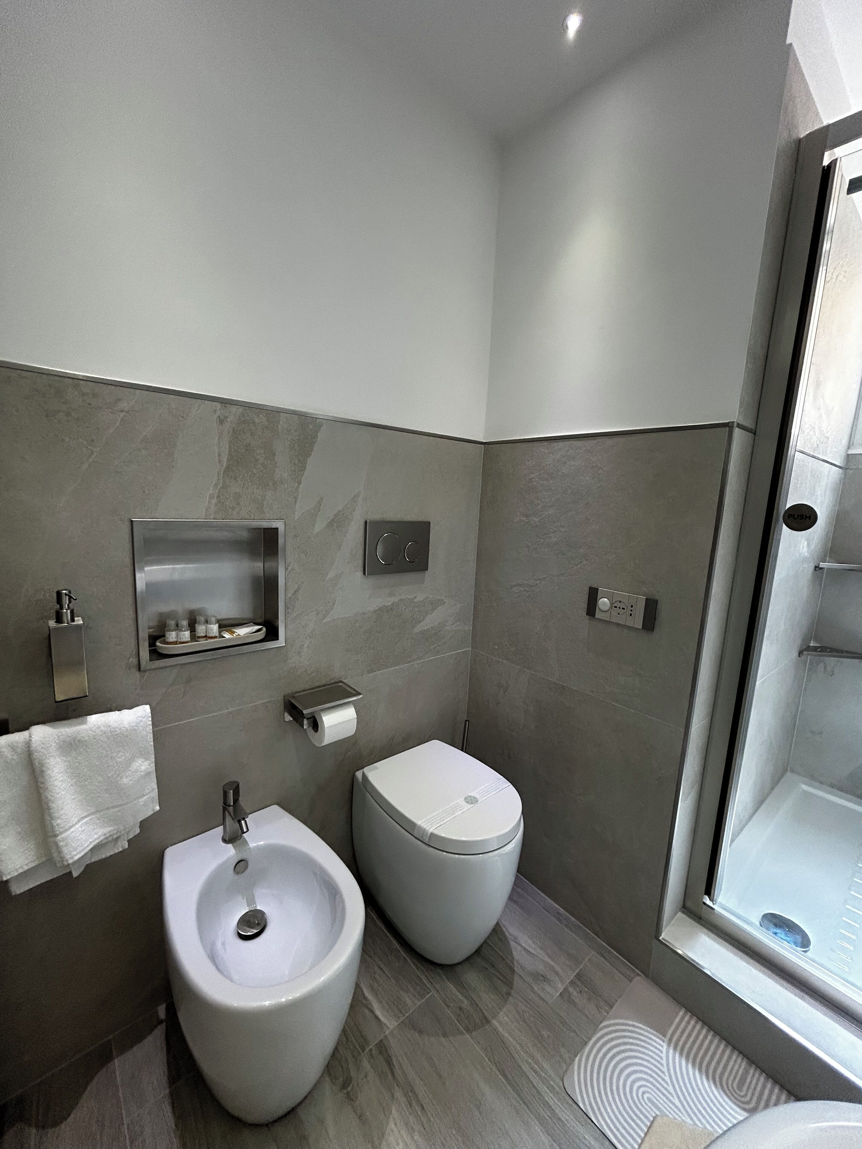 Ein modernes Badezimmer mit integriertem Bidet, Toilette und einer Duschkabine.