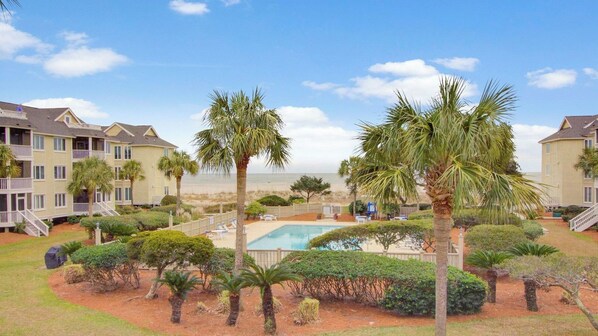 A resort with a pool, palm trees, and beach views.