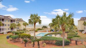 Un hotel con edificios de varios pisos, una piscina y palmeras.