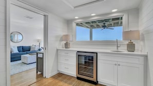 Eine moderne Küche mit weißen Schränken, einem Geschirrspüler und einem Fenster, an dem ein Deckenventilator angebracht ist.