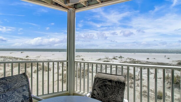 Blick auf den Strand von einer überdachten Balkon mit Tisch und Stühlen.