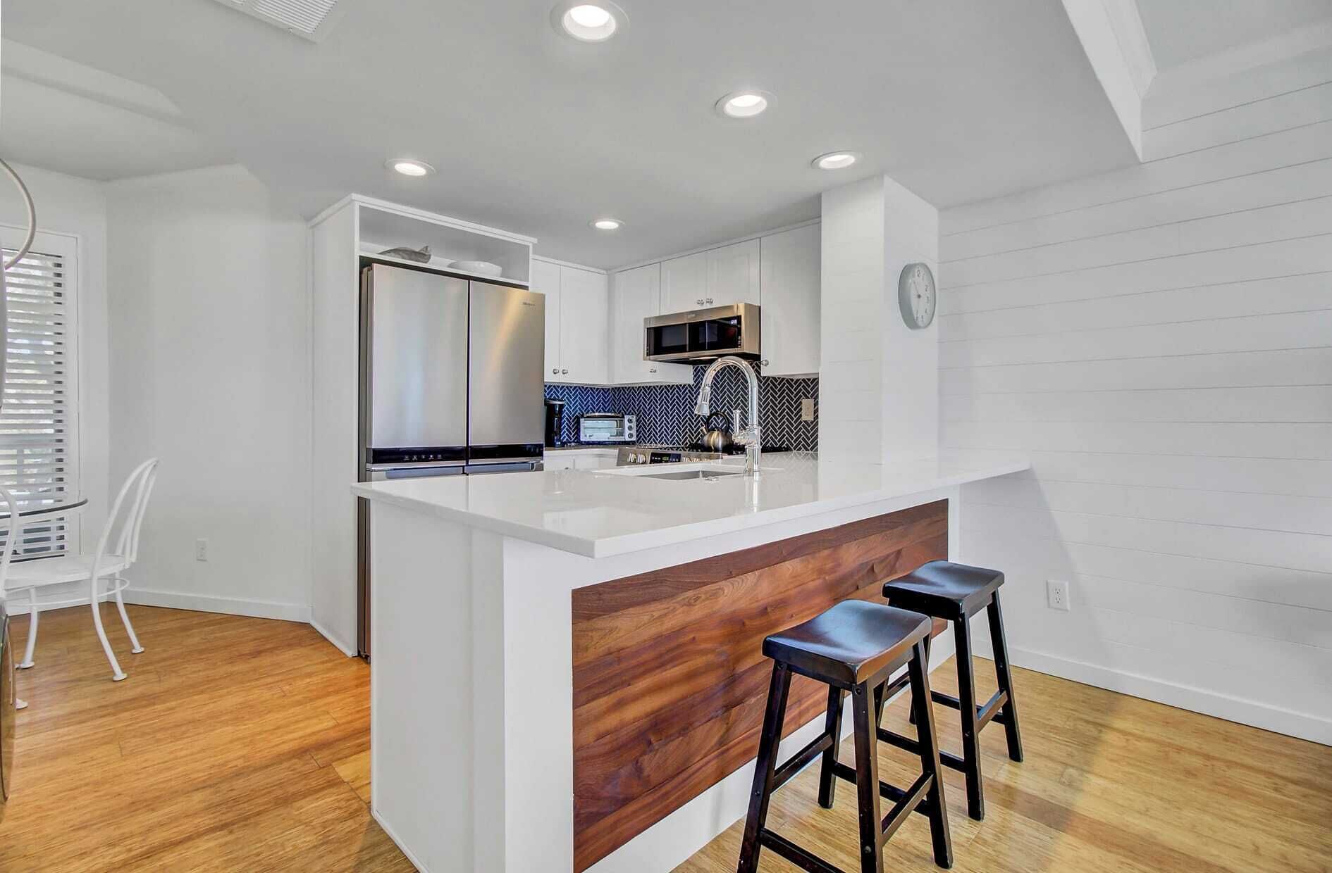 A modern kitchen with a white island, stainless steel appliances, and a wooden accent wall.