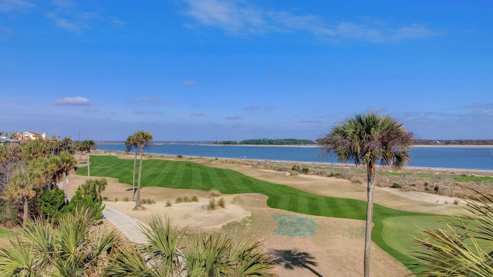 Un parcours de golf offrant une vue sur l’océan, les palmiers et un ciel dégagé.