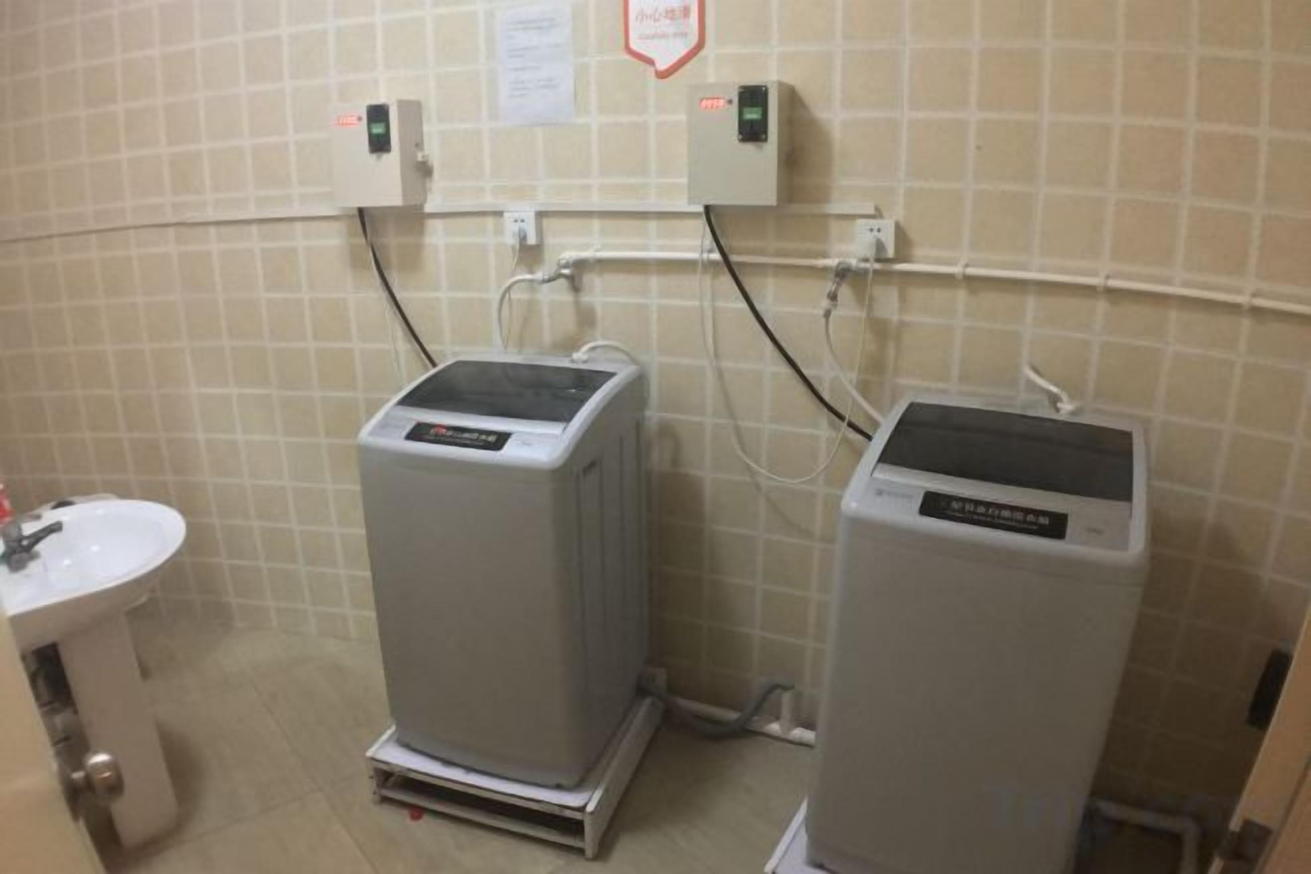 Baño con dos unidades de aire acondicionado, un lavabo y un cuadro eléctrico en la pared.