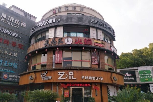 A multi-story building with a curved facade, featuring various commercial establishments including a spa and a restaurant. - 99 Inn (Shanghai Dahua Xingzhi Road Subway Station) (Shanghai)
