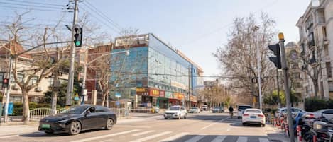 A street intersection with a modern building, crosswalk, and parked cars.