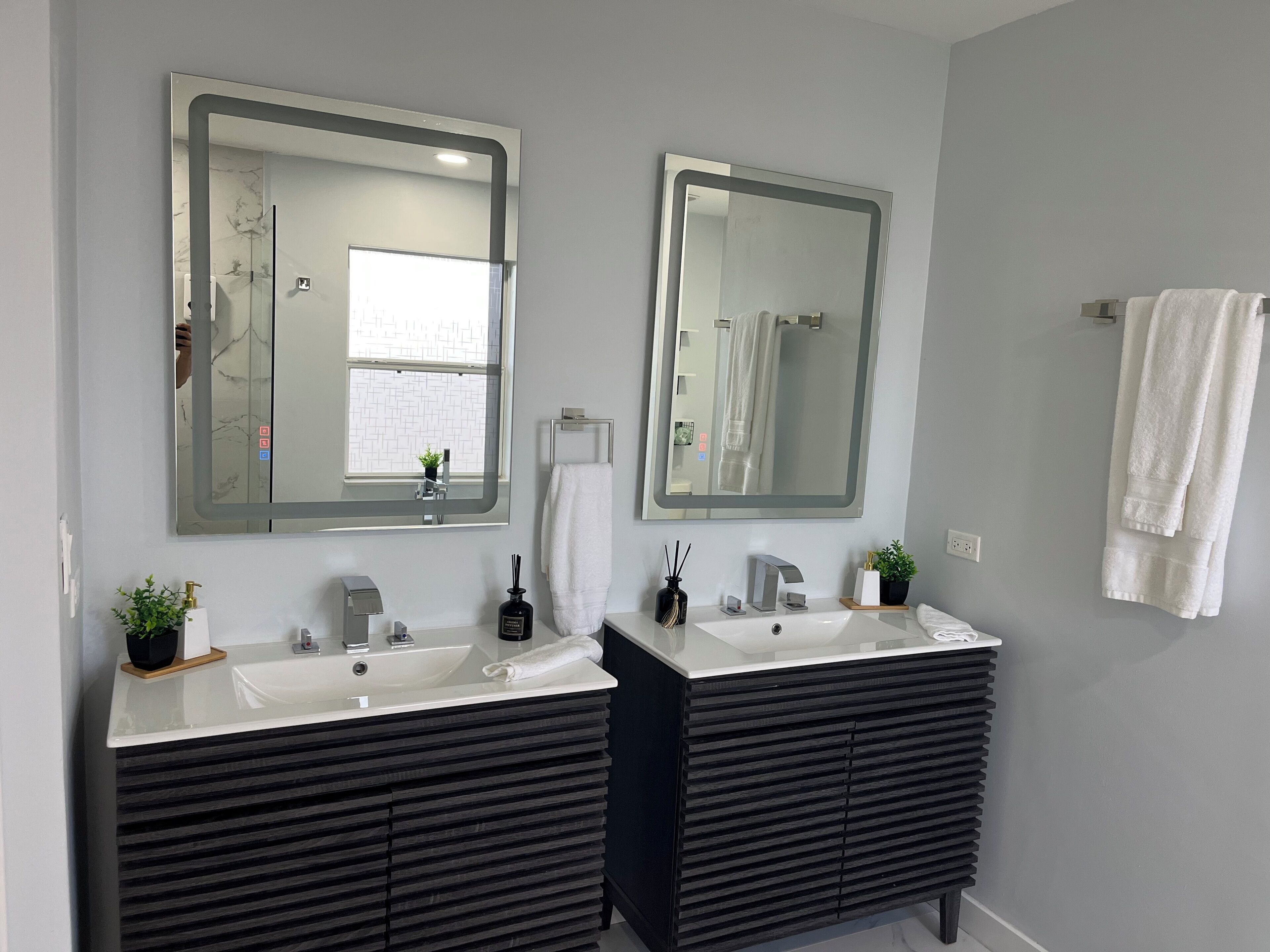 Une salle de bain moderne avec deux lavabos, un grand miroir et un porte-serviettes.