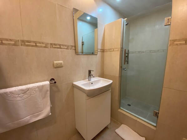 A bathroom with a sink, mirror, and glass shower enclosure. - Paseo Colonial - Ermitage 5 (Santo Domingo)