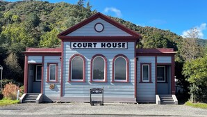 A courthouse with a sign reading "COURT HOUSE" above the entrance, featuring a symmetrical facade with three arched windows and a central circular window.