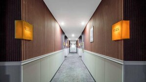 A hotel hallway with wooden paneling, a carpeted floor, and illuminated room numbers. - Taizhou Western Style Hotel (Taizhou)
