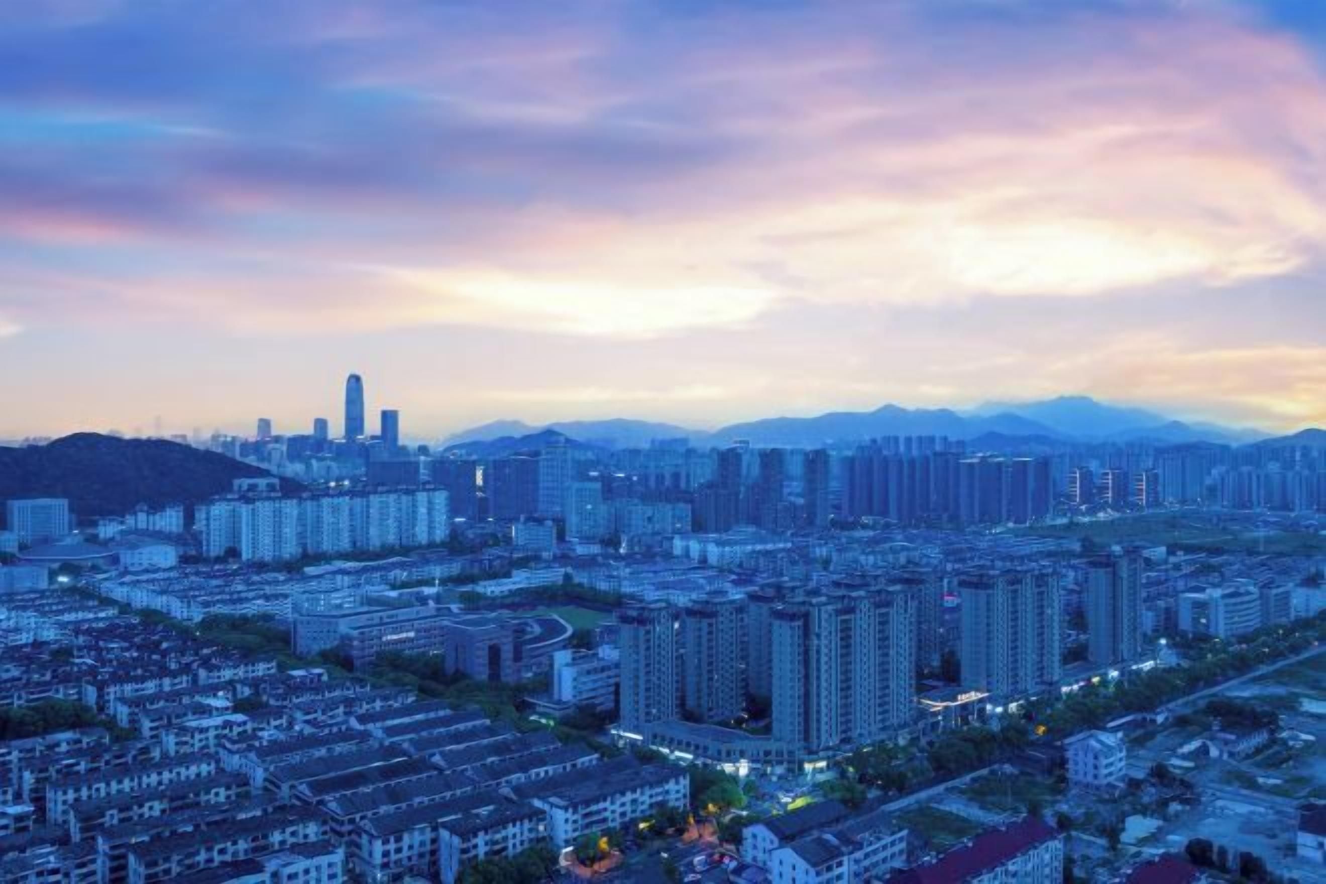 A cityscape with high-rise buildings and a distant mountain range.