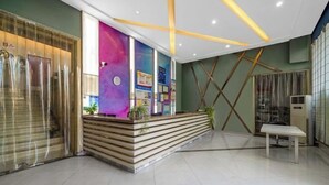 A reception area with a wooden counter, a colorful wall with posters, and a modern ceiling design. - Taizhou Western Style Hotel (Taizhou)