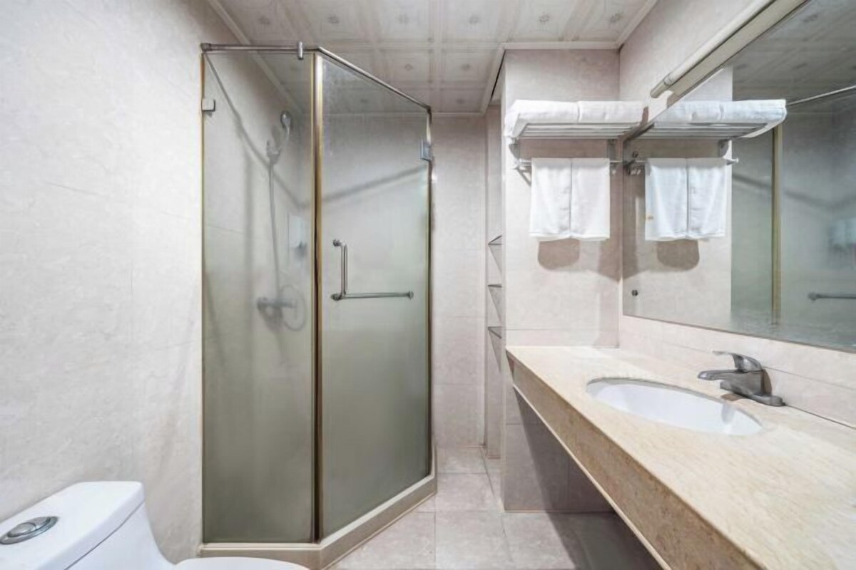 Un baño con ducha de vidrio, lavabo y espejo.