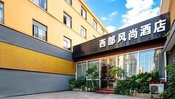A hotel entrance with a modern facade, large windows, and a clear sky.