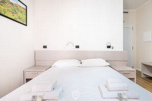 Una habitación de hotel moderna con una cama grande, dos mesitas de noche y un televisor montado en la pared.