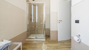 A modern bathroom with a glass-enclosed shower, a toilet, and a sink.